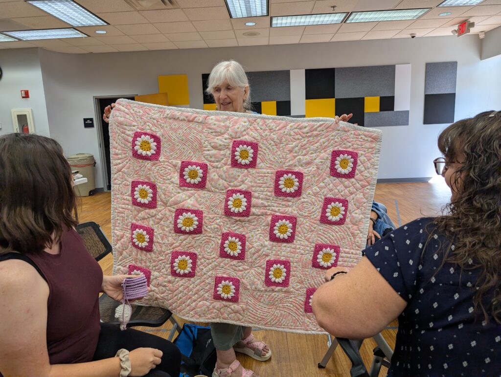 18 daisy flower granny square blocks on hot pink were appliqued to a light pink fabric for this small quilt bound in white.