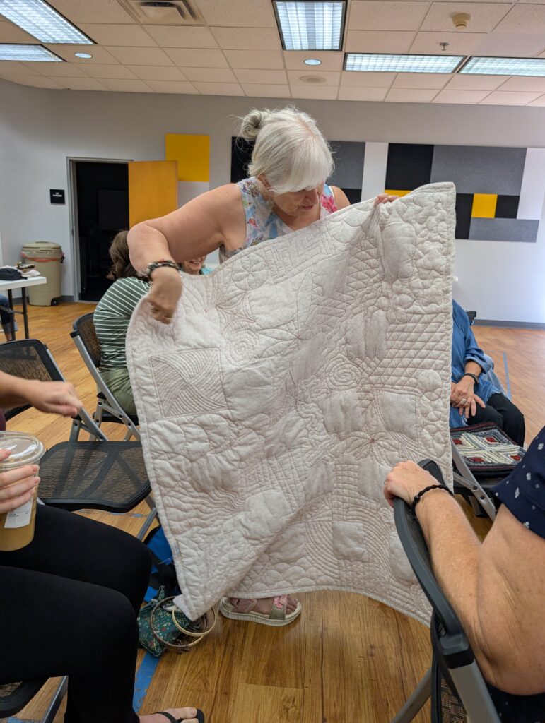The back side of the granny square quilt is solid white, but shows off the diversity of different quilting patterns used.