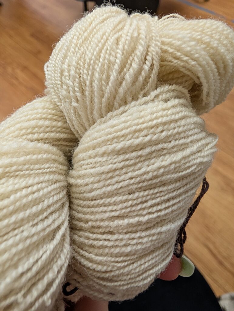 Close up of a skein of finely spun 2 ply wool yarn. The wool is white. The singles were spun on a spindle, and plied on a wheel.